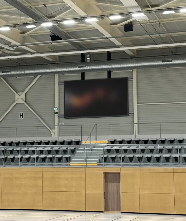 Grand écran LED dans un équipement sportif couvert.